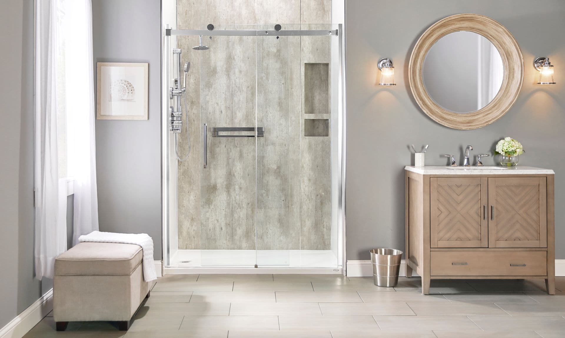 A wide shot of a gray bathroom with a bench on the left, a Jacuzzi Shower with Farm Walls and sliding doors in the center, and a beige vanity and mirror on the right.