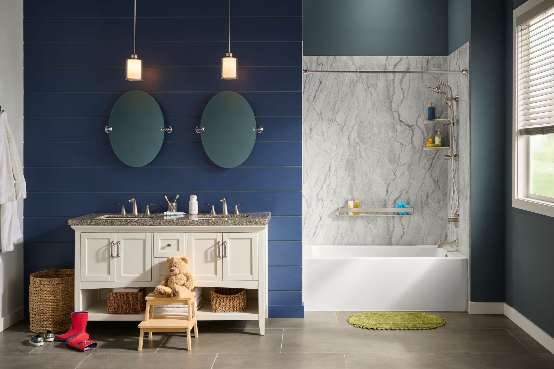 A head on photo of a blue bathroom with a BathWraps Smooth Granite River Modern Family shower and tub combination. A teddy bear is sitting on a step stool in front of the vanity.
