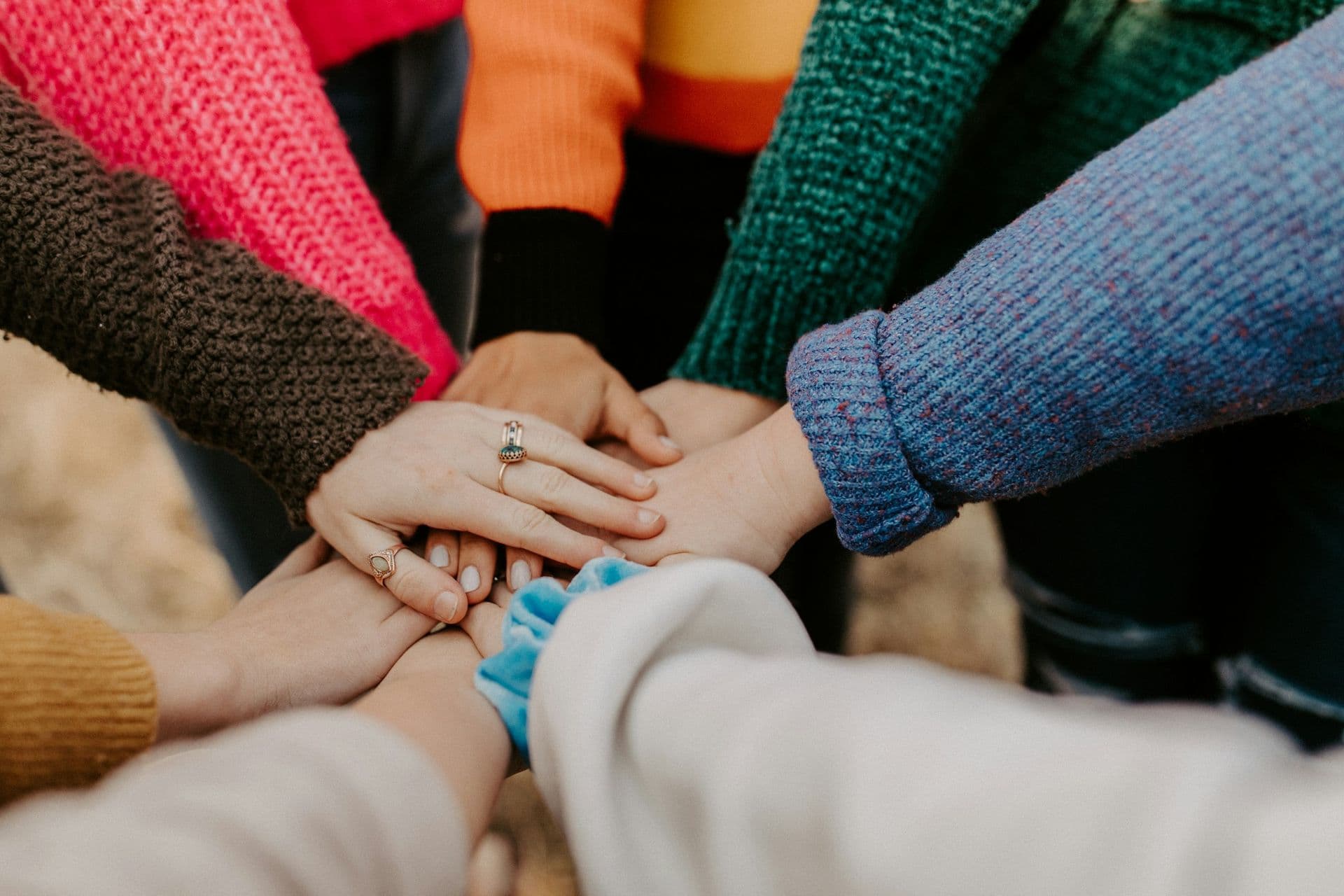A group of people stack their hands together in a circle.